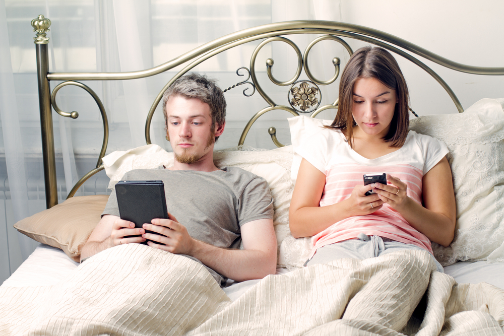 couple in bed with phones