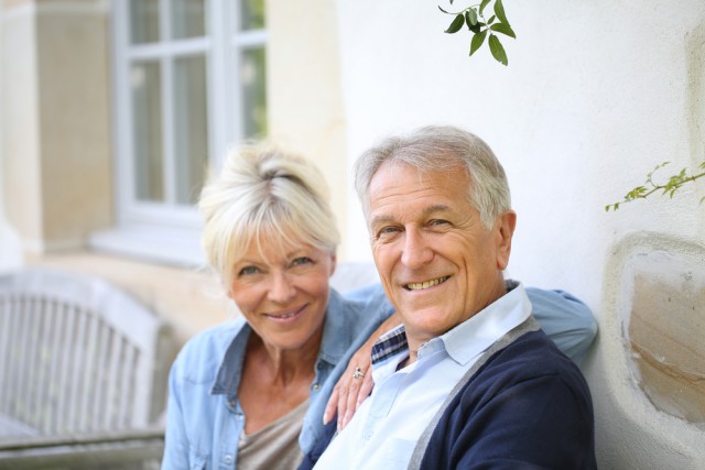 Elderly couple smiling sitting on a porch bench