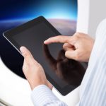 Man holding an iPad tablet on a plane next to the window