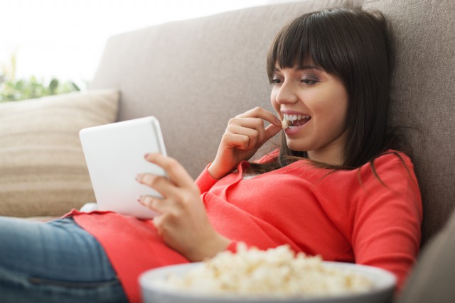 Woman tablet streaming watching video popcorn couch