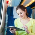 Young woman using her tablet computer while traveling by train