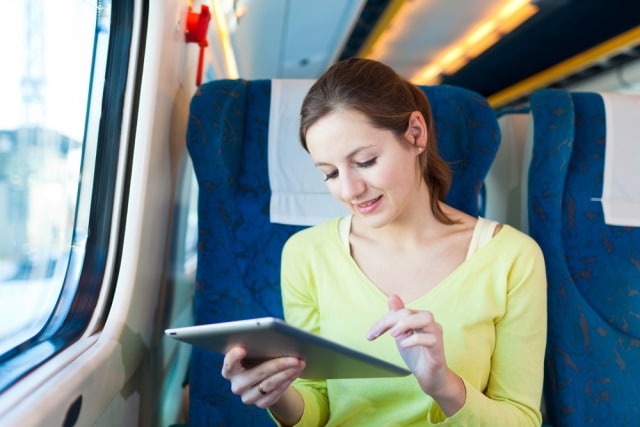 Young woman using her tablet computer while traveling by train