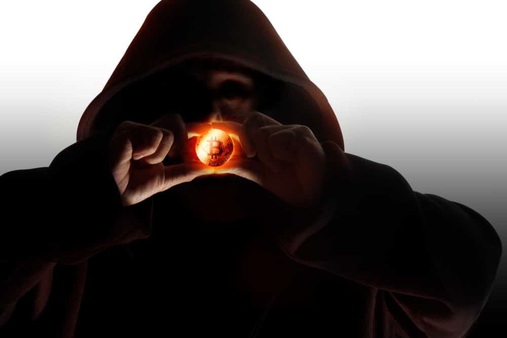 Hooded,Man,In,Shadow,Holding,Cryptocurrency,Bitcoin,On,Dark,Background.