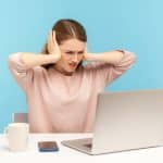 Woman at laptop covering ears