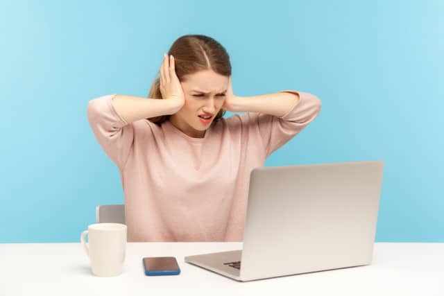 Woman at laptop covering ears