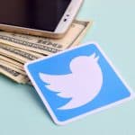 Twitter logo next to dollars and smartphone