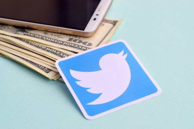 Logo Twitter di sebelah dolar dan smartphone