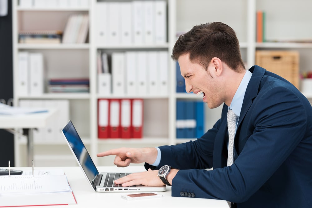 Businessman screaming and pointing at his laptop