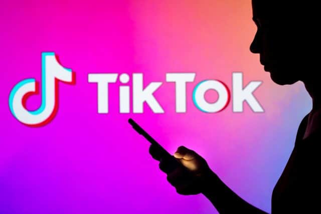 Logo TikTok dengan siluet pengguna di latar depan