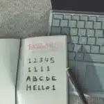 Passwords written a notebook on top of a laptop