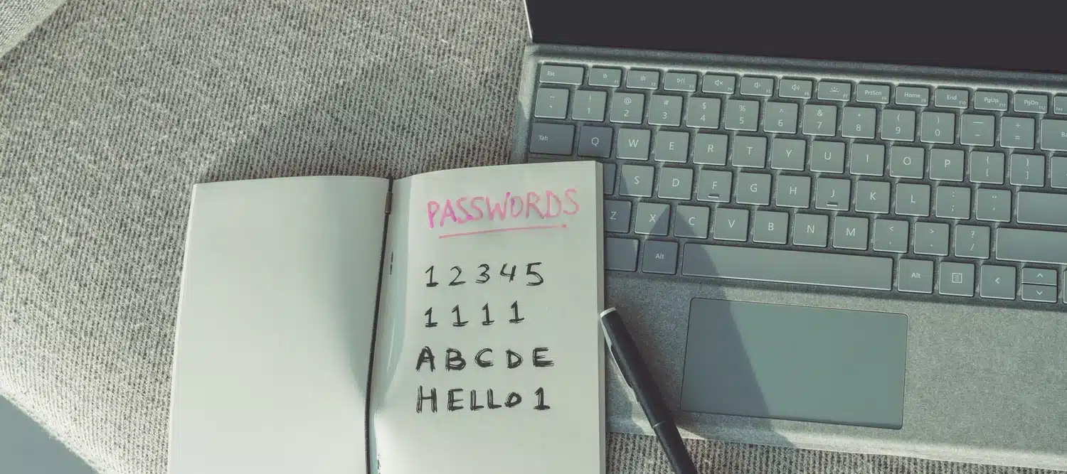 Passwords written a notebook on top of a laptop