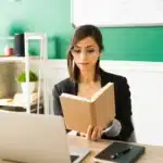 Woman reading book at computer