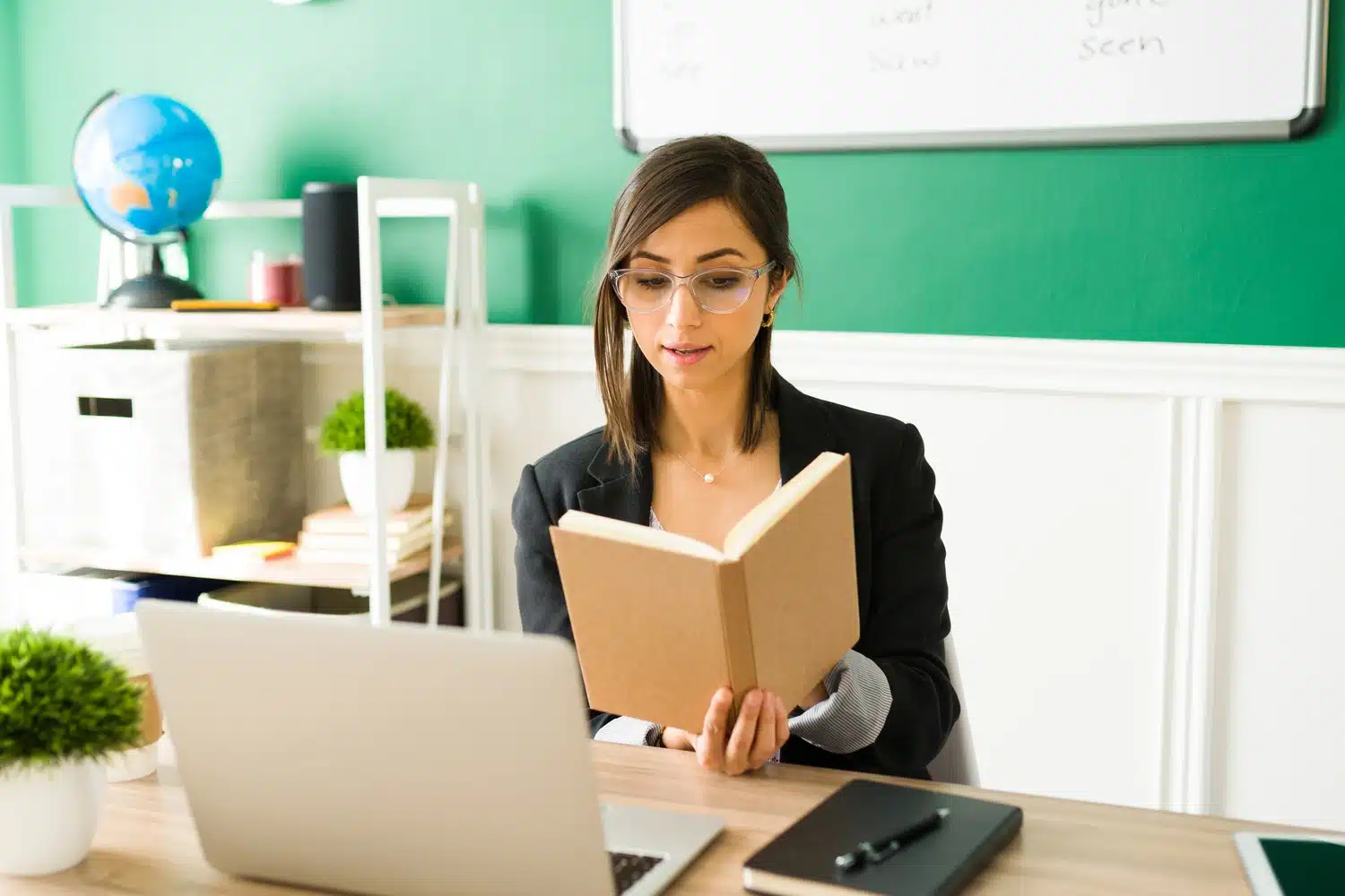 Woman reading book at computer