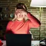 Woman at laptop hiding eyes