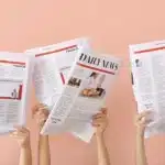 Hands holding newspapers in the air