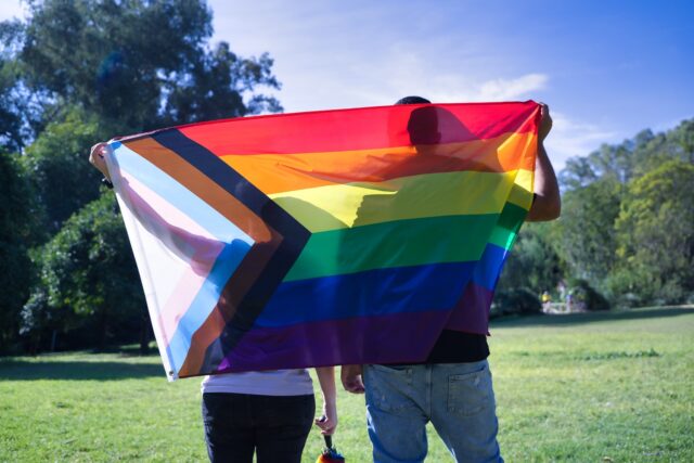 Two people holding a pride flag