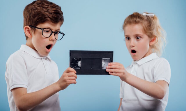 Boy and girl looking at a VHS cassette