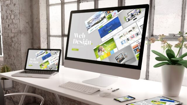 a computer and laptop on a desk showing website design