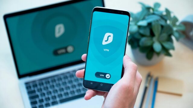 a person holding a phone showing Surfshark VPN