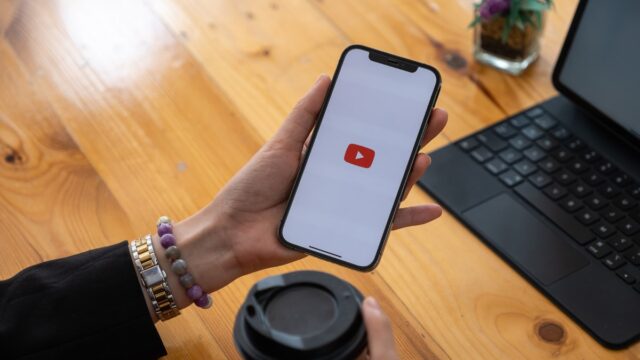 Рука, держащая телефон с логотипом YouTube