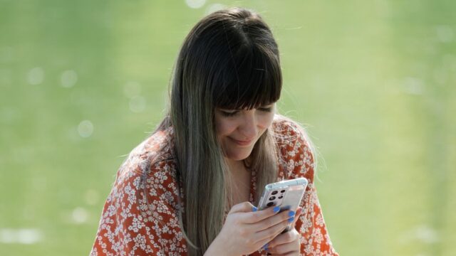 Woman using smartphone by water.