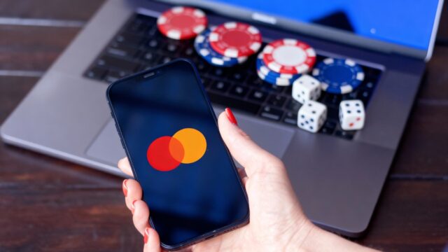 Mastercard app displayed on a phone next to a laptop with poker chips